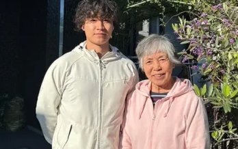 若い男性スタッフが高齢女性と一緒に庭先で笑顔で撮影した写真